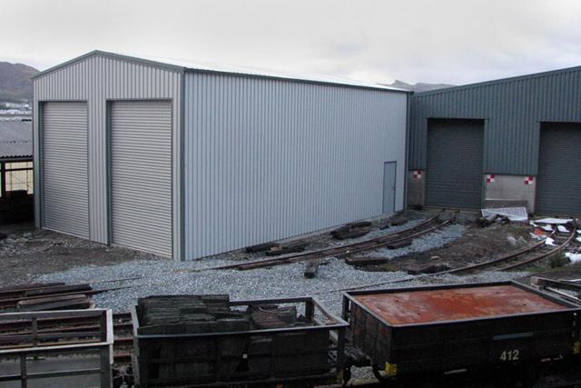 A dual-doored grey building on a train yard